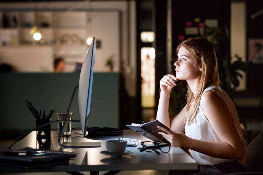 An image of a woman in office working late
